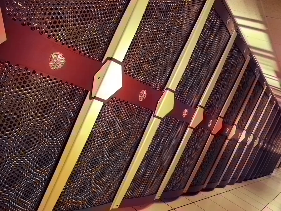 A long row of supercomputer racks with perforated doors, seen at an angle.