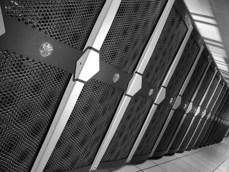 A long row of supercomputer racks with perforated doors, seen at an angle.